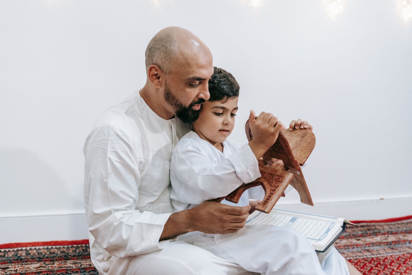 Un père accompagne son fils dans la lecture du Coran.